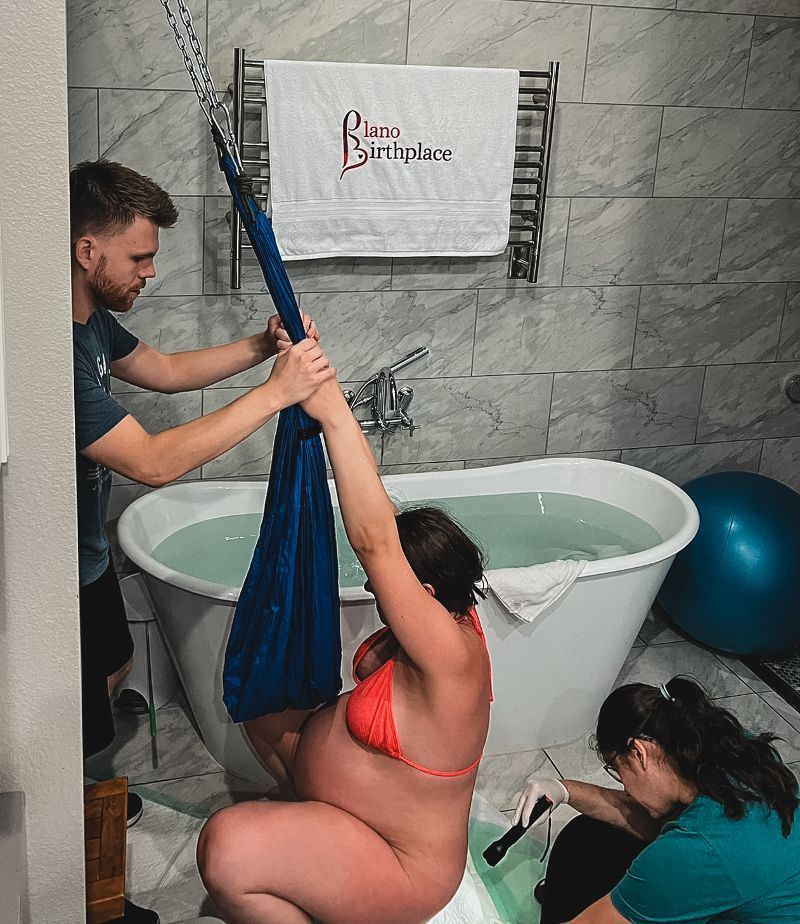 A man is helping a pregnant woman give birth in a bathtub.