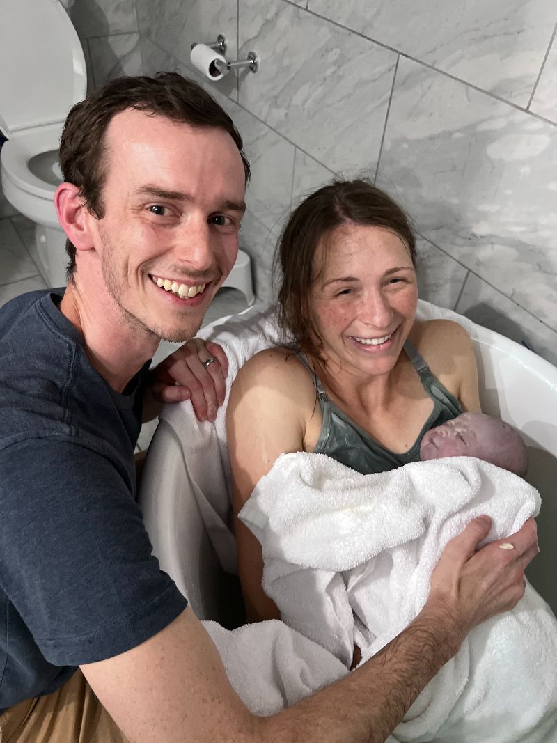 A man and woman are holding a baby in a bathtub.