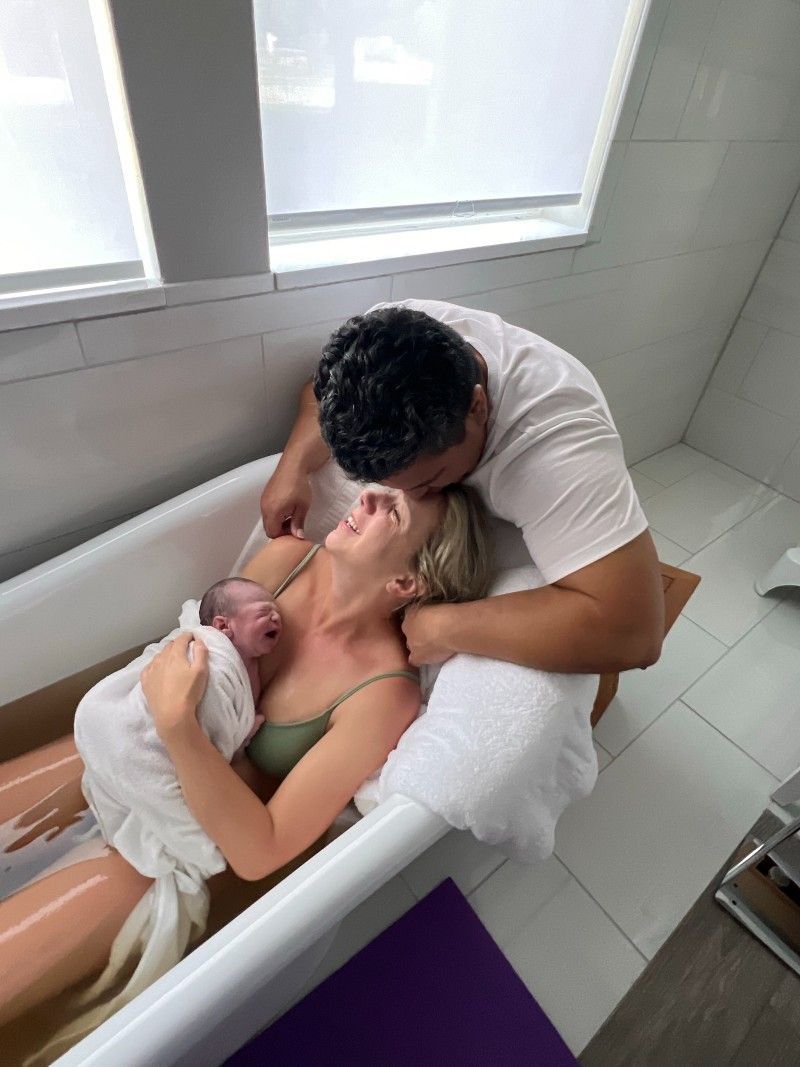A woman giving birth using a water treatment while her husband assisting her