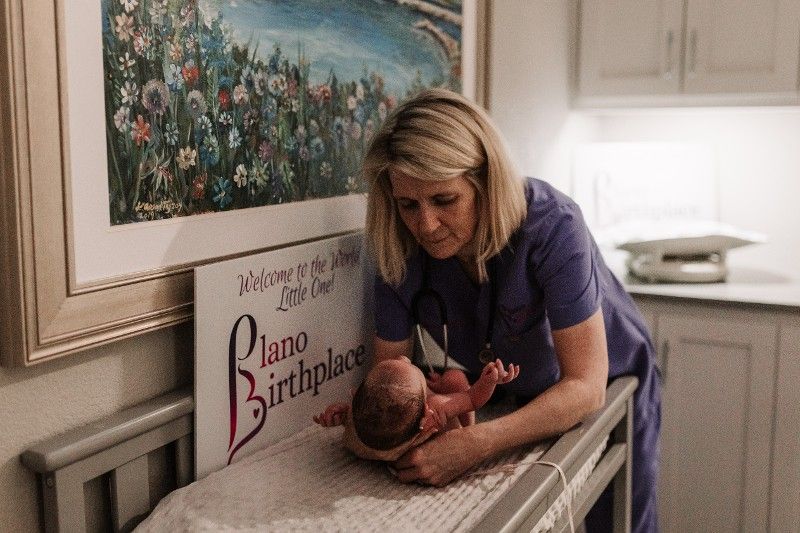 A nurse is holding a newborn baby on a changing table.