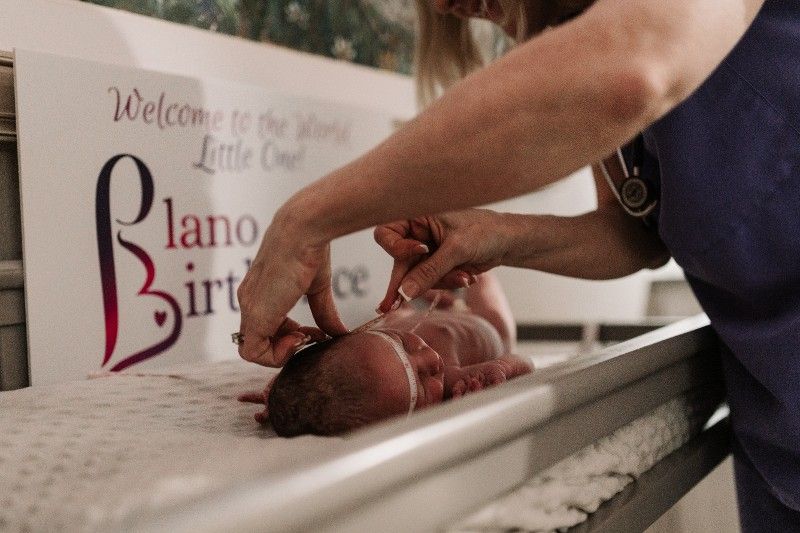 A nurse is examining a newborn baby on a changing table.