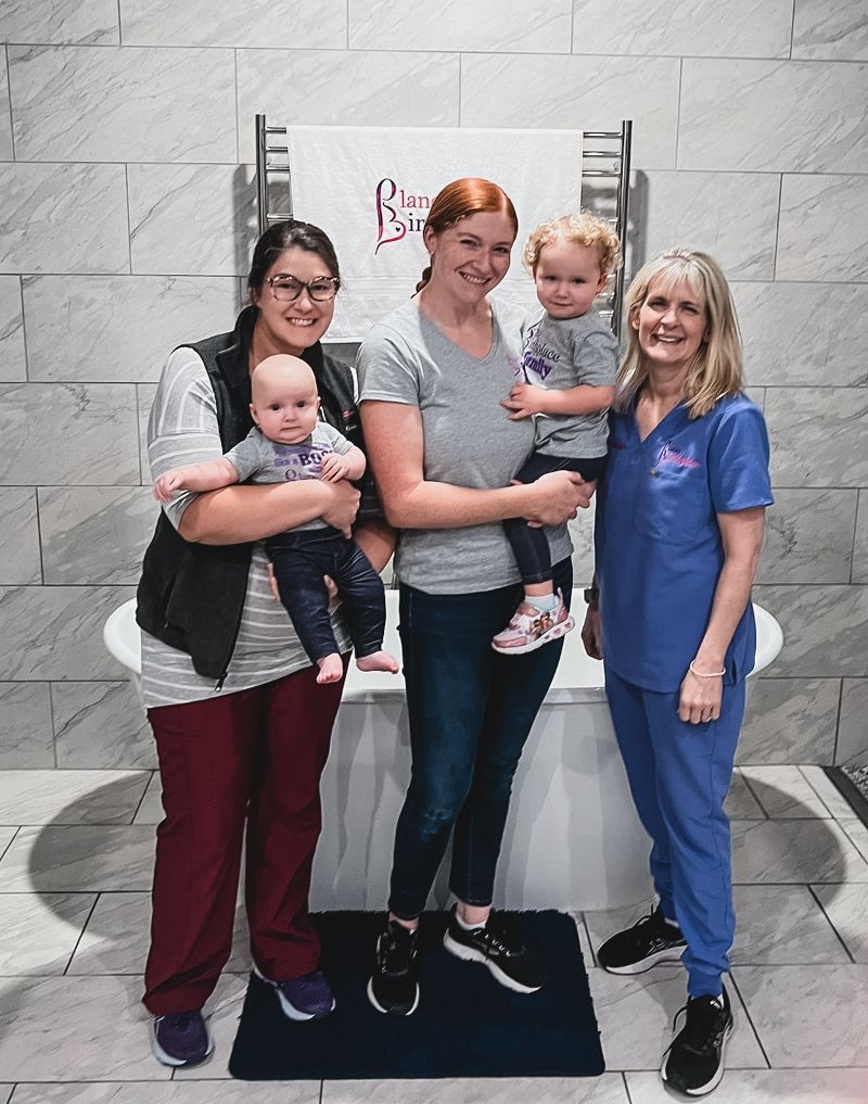 A group of women standing next to each other holding babies.