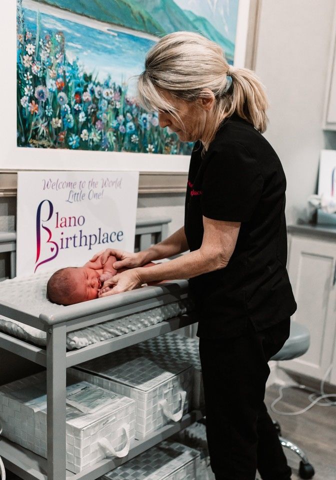 A woman is putting a newborn baby on a changing table.