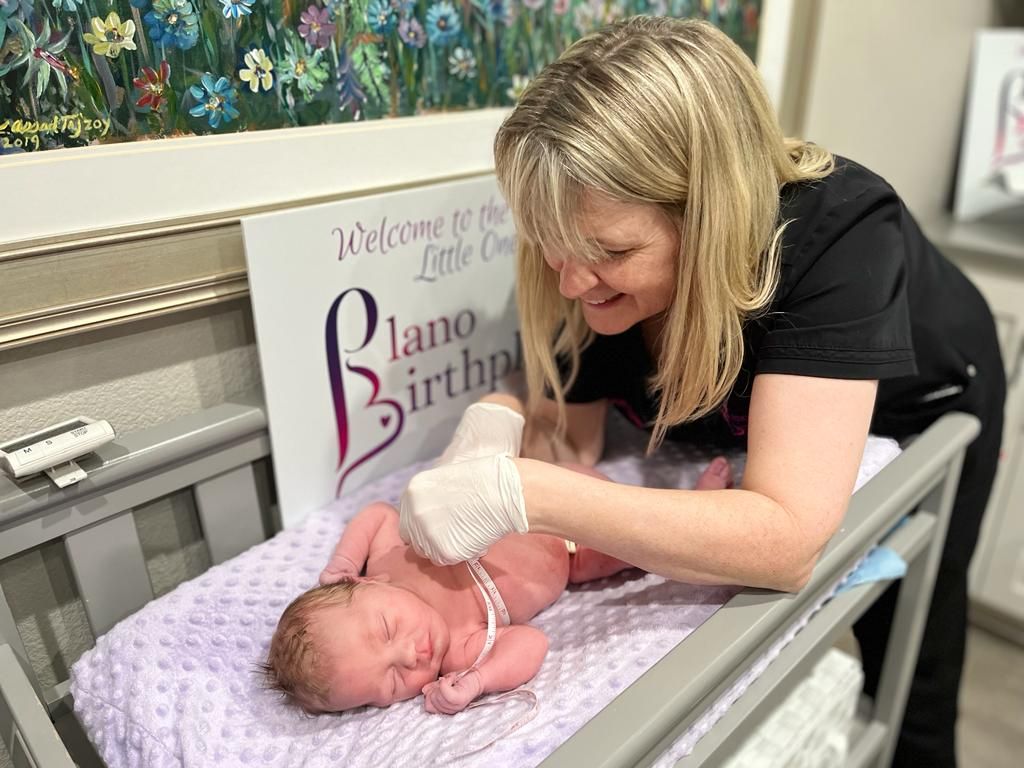 A woman is holding a newborn baby in a crib.