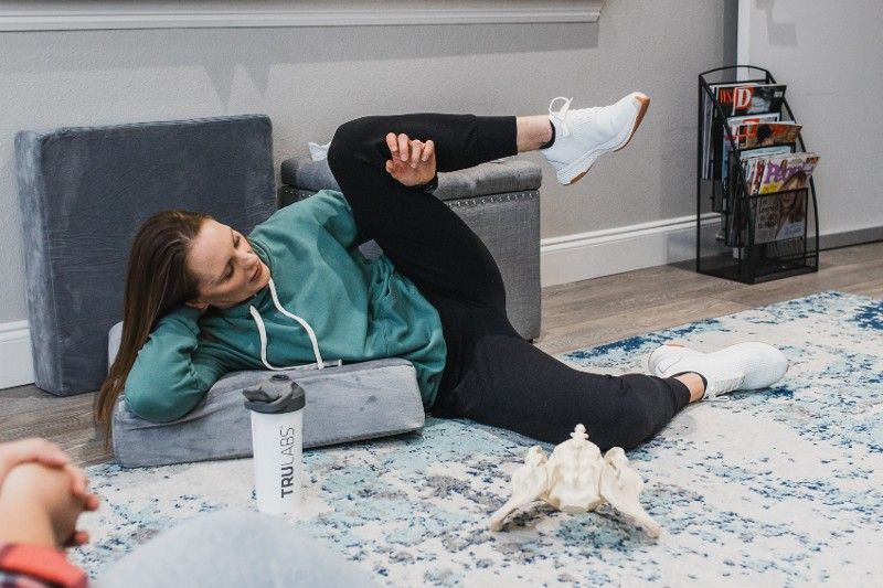 A woman is laying on the floor stretching her legs.