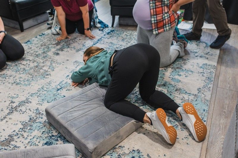 A woman is laying on her stomach on a pillow on the floor.