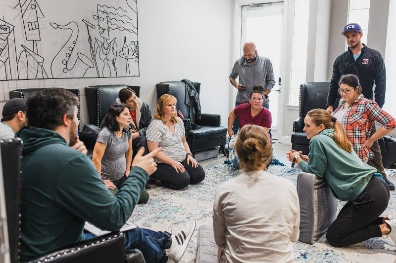 A group of people are sitting in a circle in a living room.