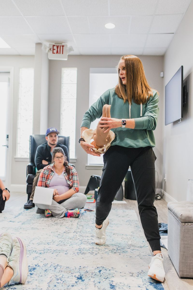 A woman is holding a stuffed animal in front of a group of people.