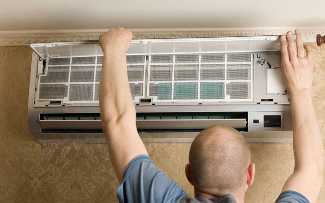 Man cleaning air conditioner filter, indoors.