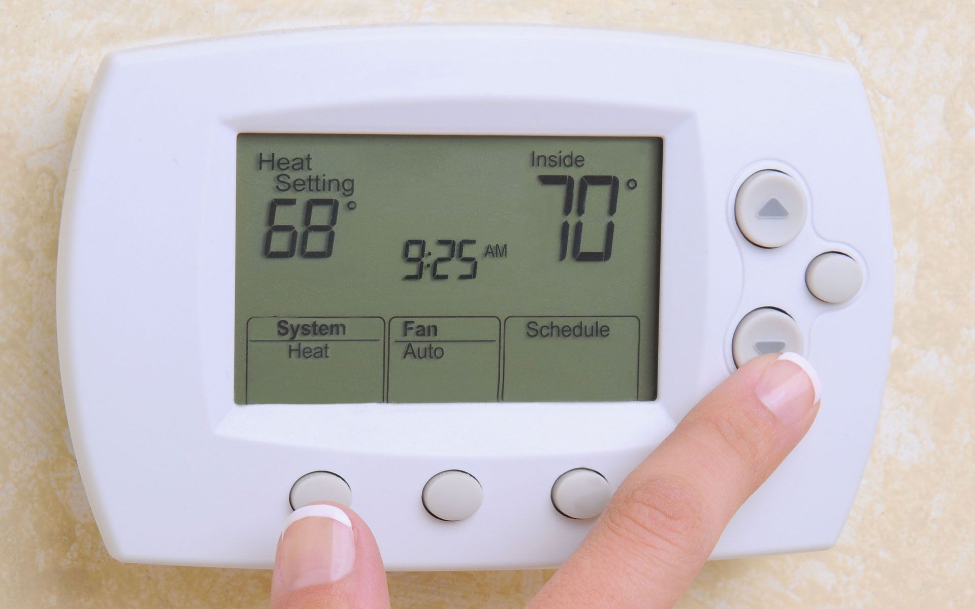 A hand adjusts a thermostat, setting it to 70 degrees. The display shows a current setting of 68 degrees.