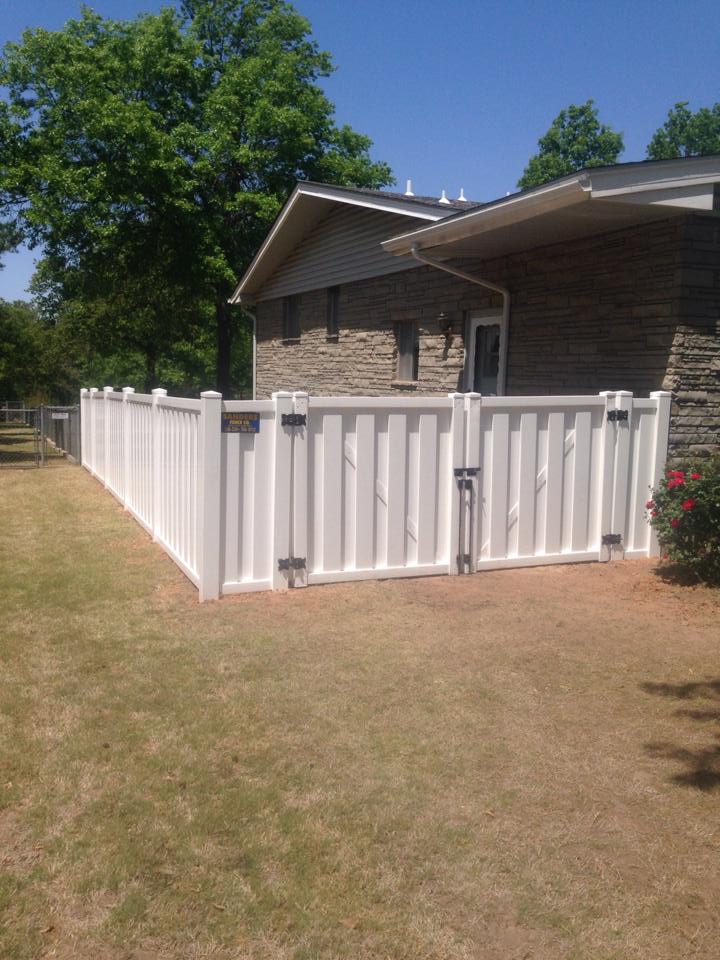 A white fence is in front of a house.