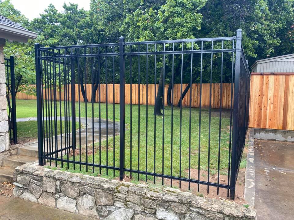 A black metal fence surrounds a lush green yard.