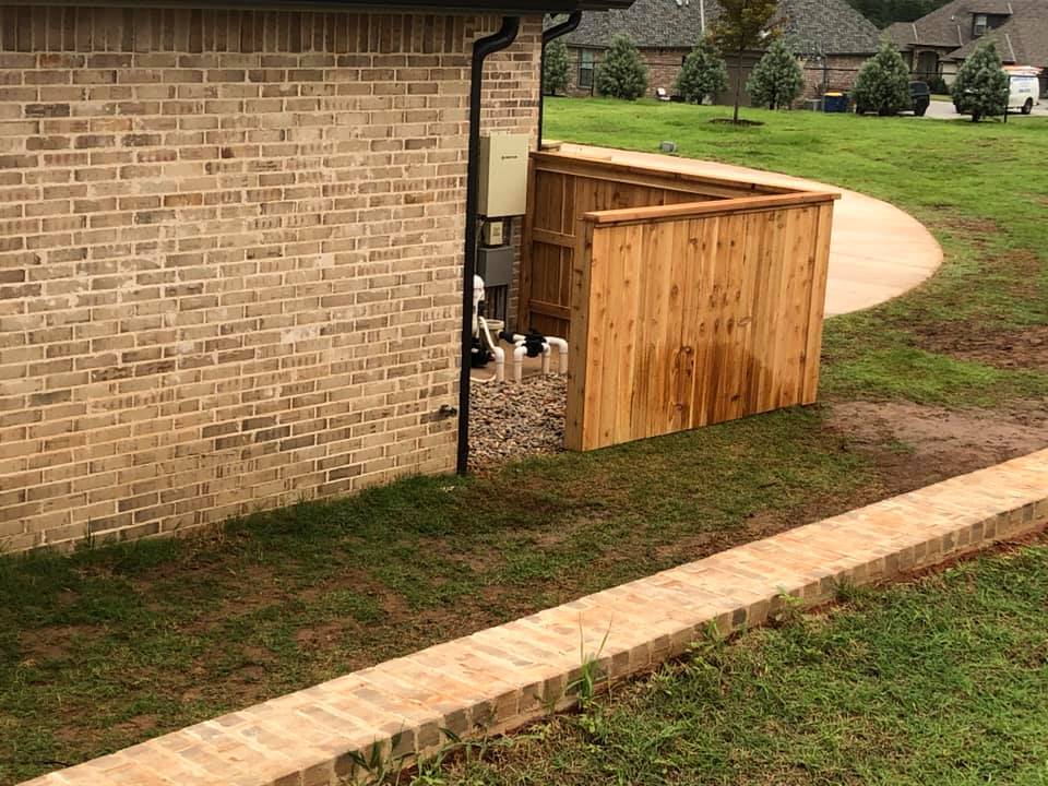 A wooden fence is sitting next to a brick wall.