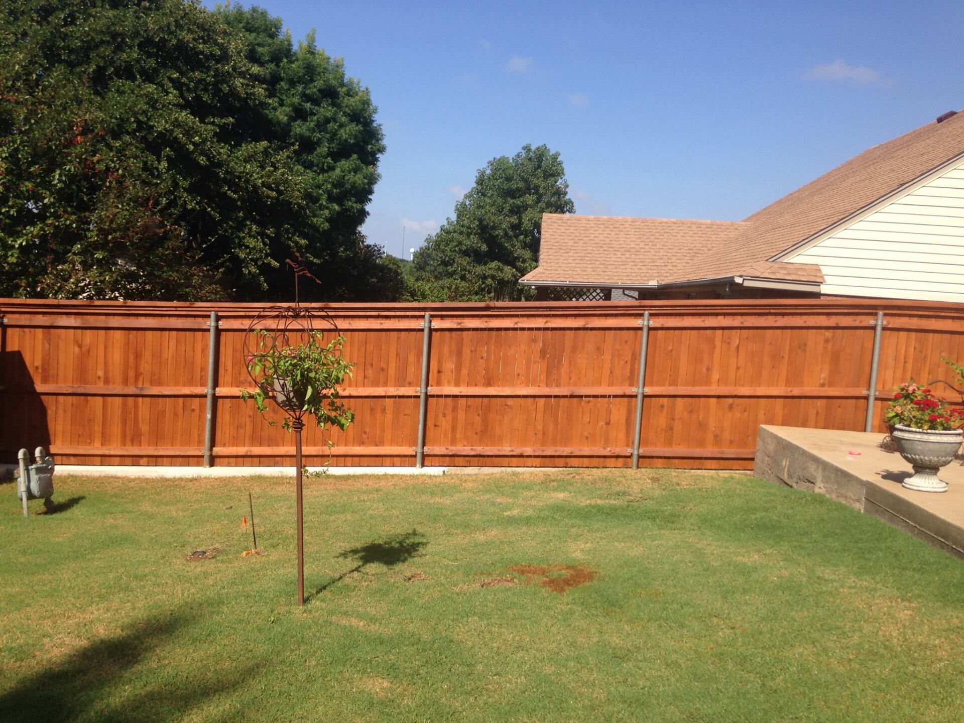A wooden fence surrounds a lush green yard in front of a house