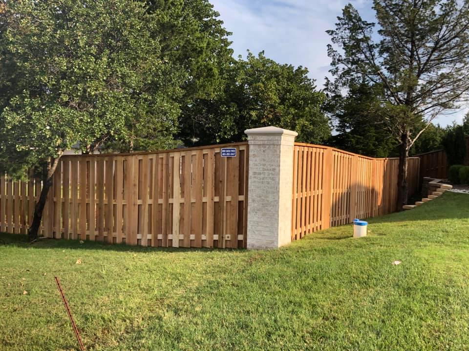 A wooden fence is in the middle of a lush green field.