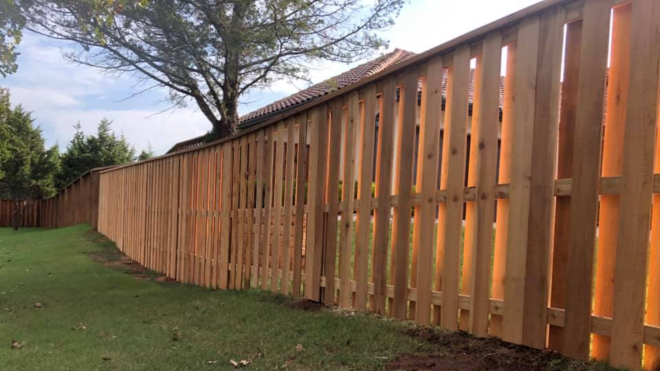 A wooden fence is sitting in the middle of a lush green field.