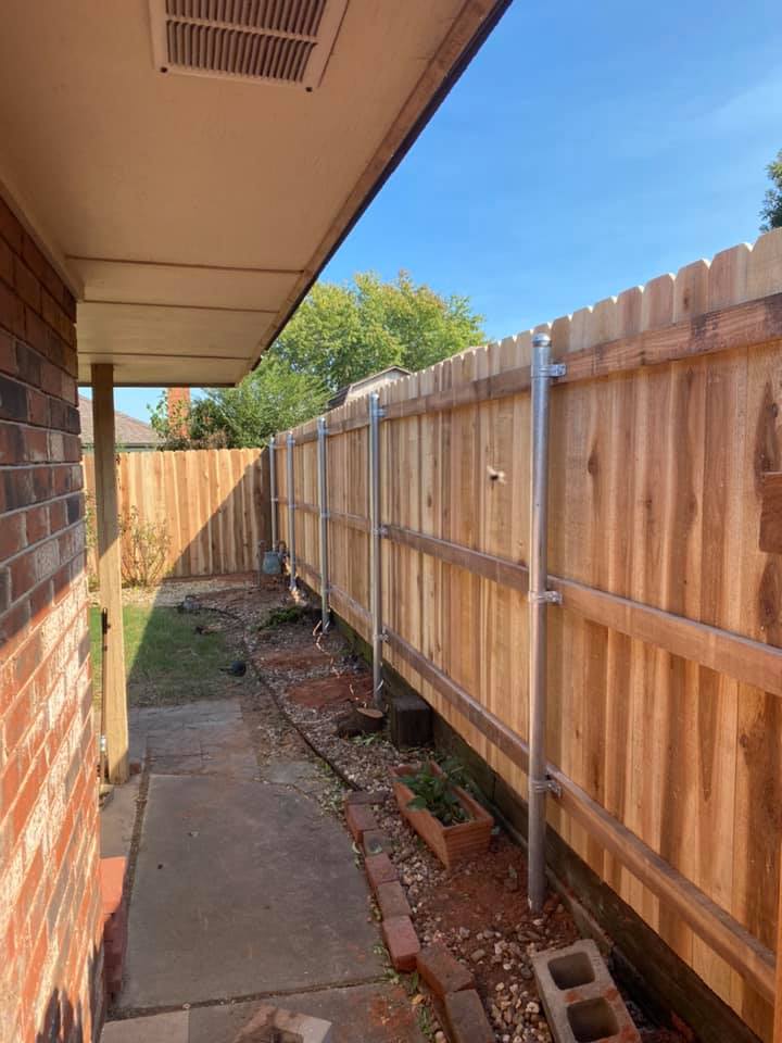 A wooden fence is being built in the backyard of a house.