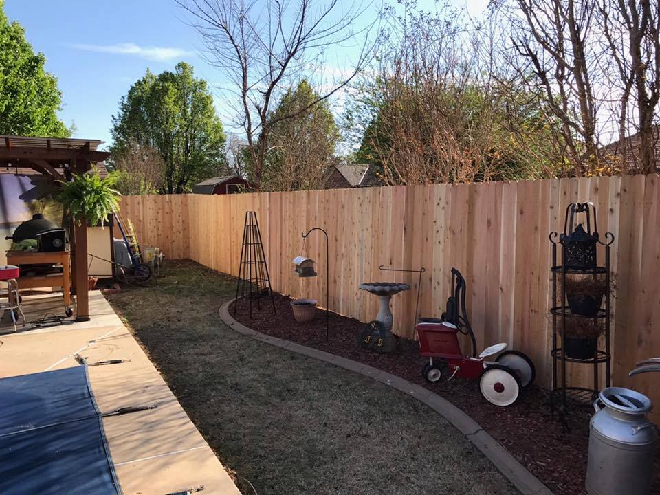 A backyard with a wooden fence and a red wagon.