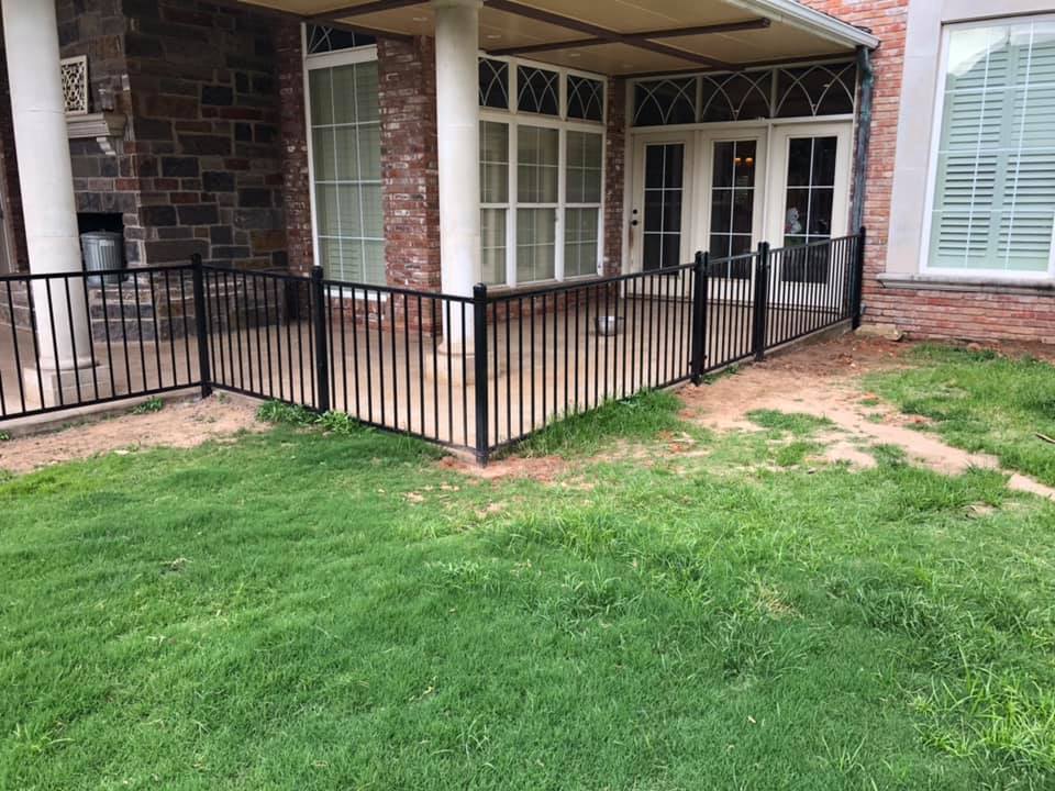 A patio with a fence around it and a brick building in the background.
