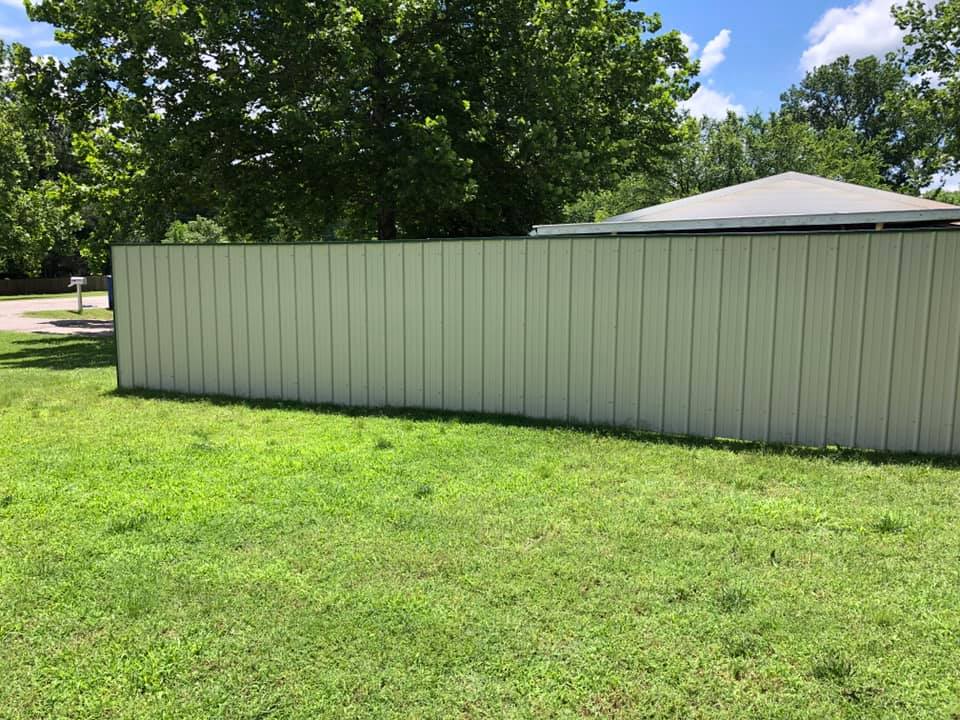 A white fence is sitting in the middle of a lush green field.