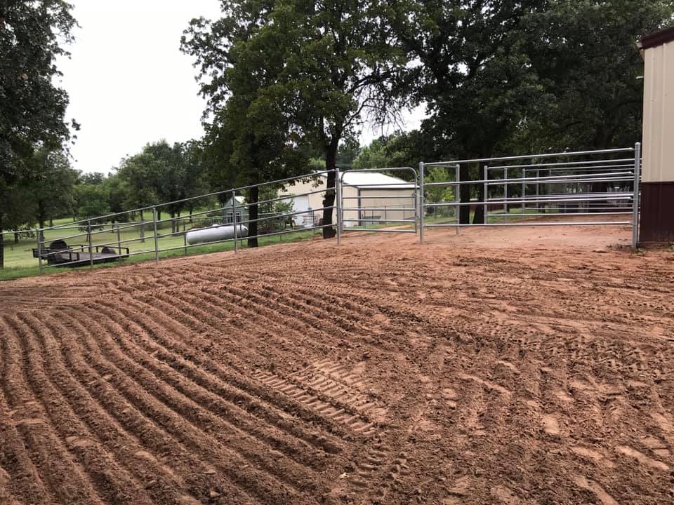 A dirt field with a gate and trees in the background