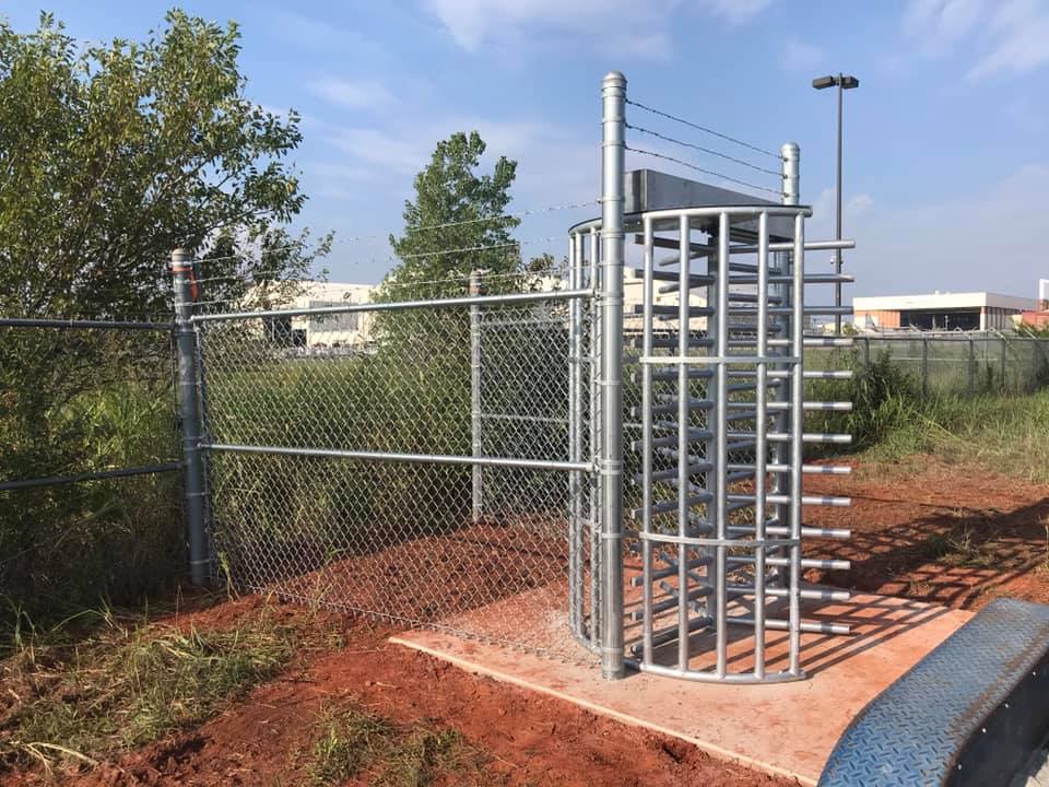 A metal gate is surrounded by a chain link fence.