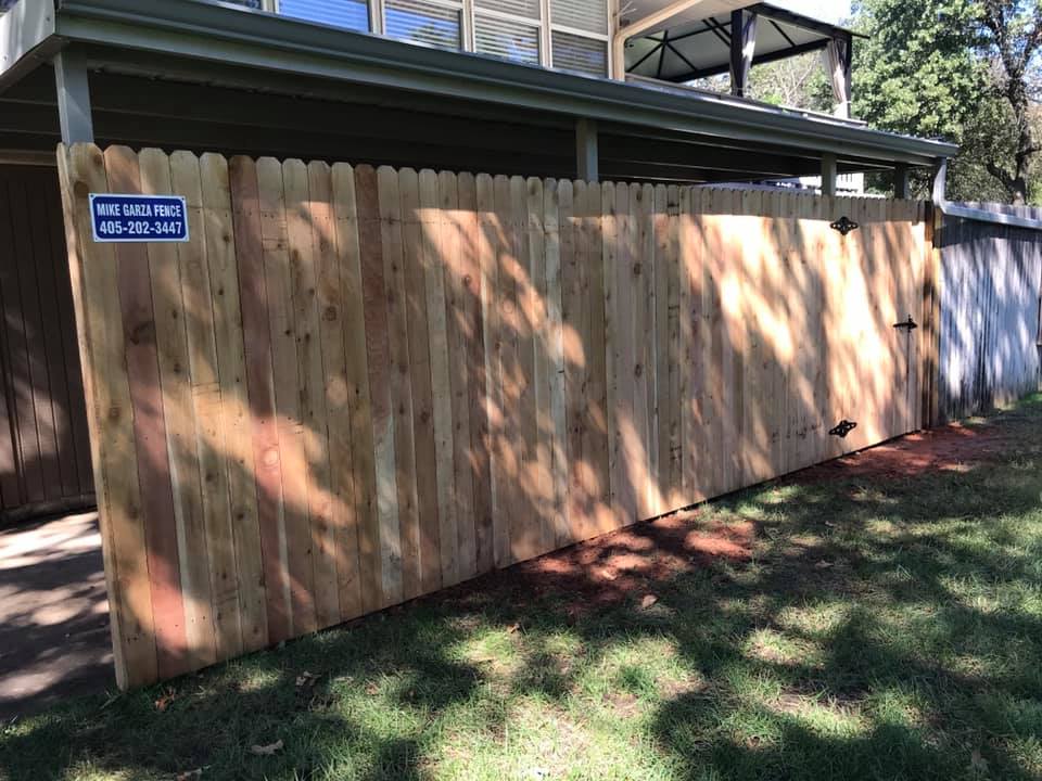 A wooden fence is sitting in the grass in front of a house.