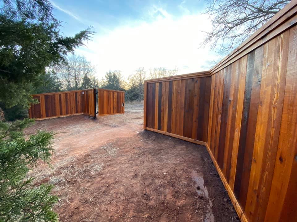 A wooden fence surrounds a dirt path in a backyard.