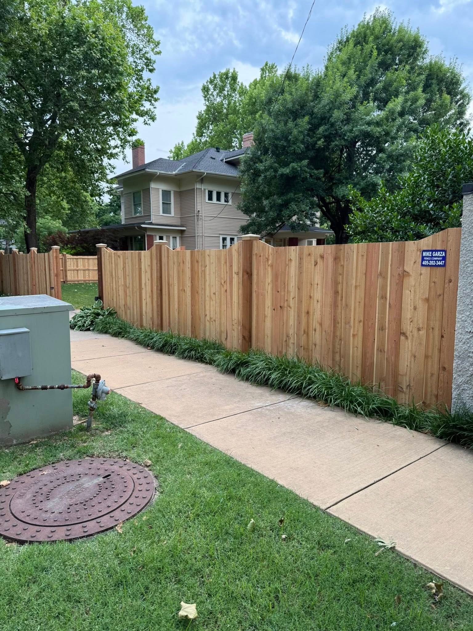A wooden fence along a sidewalk in front of a house.
