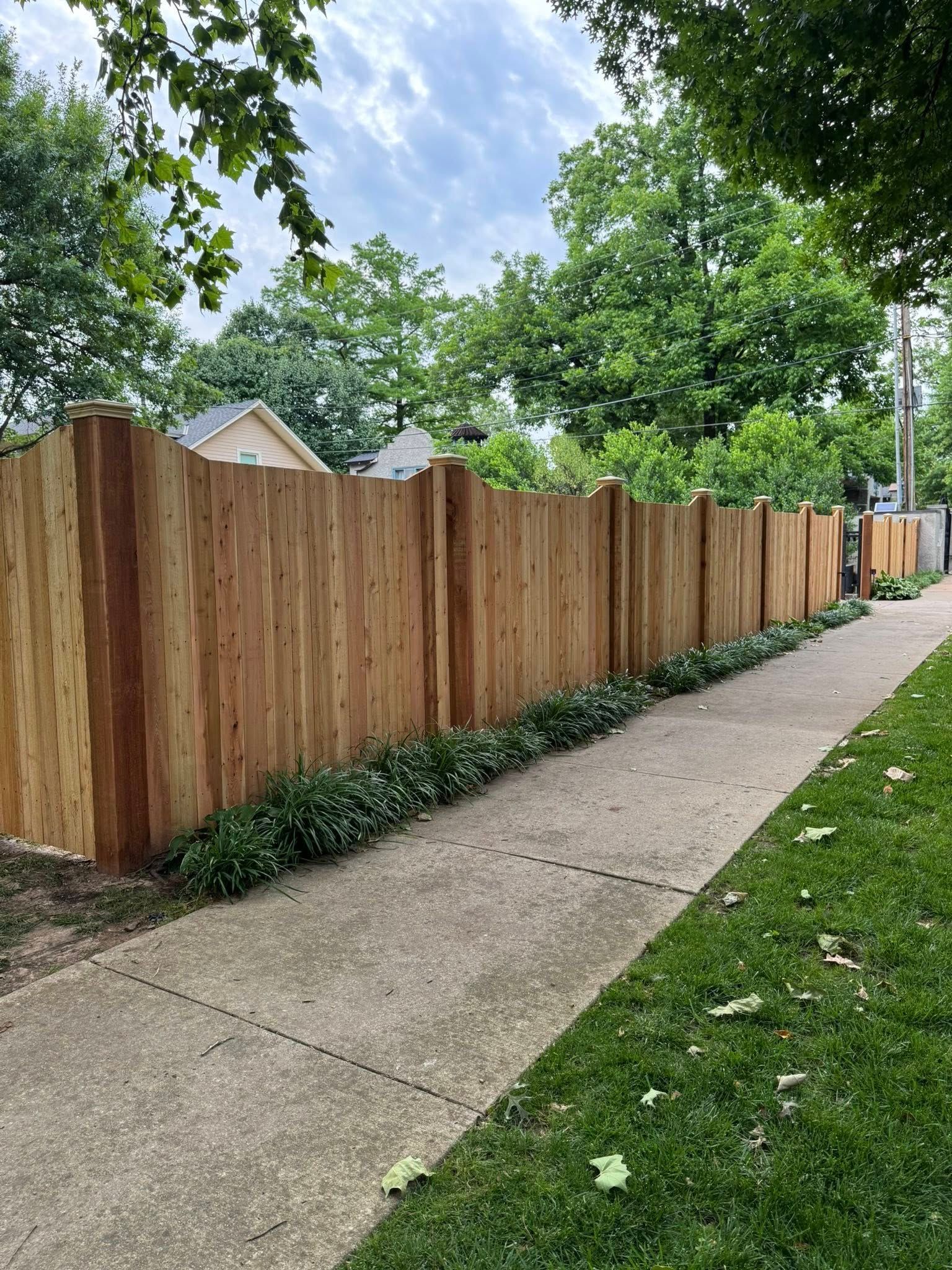 A wooden fence along a sidewalk next to a house.
