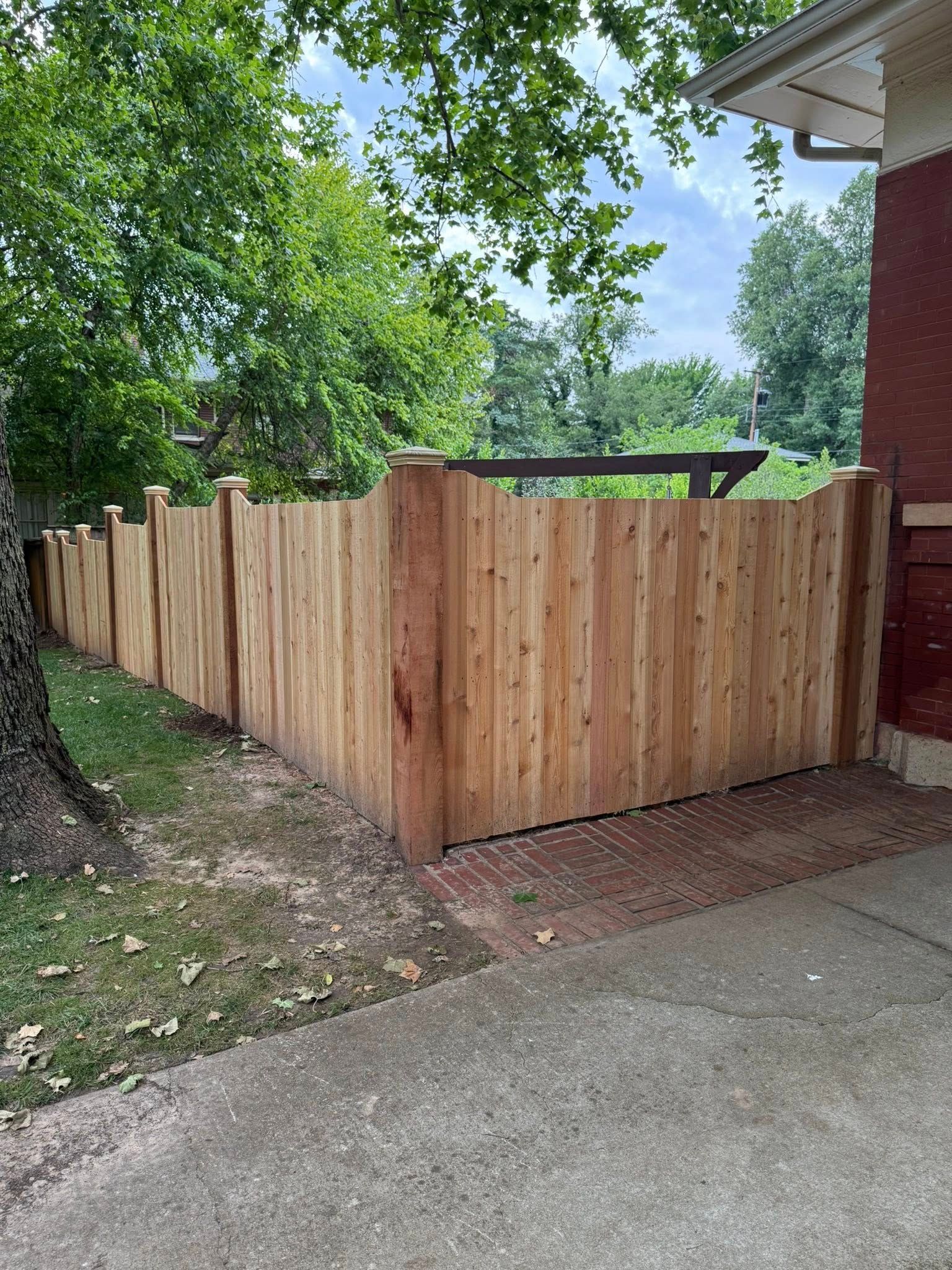 A wooden fence is sitting in front of a brick house.