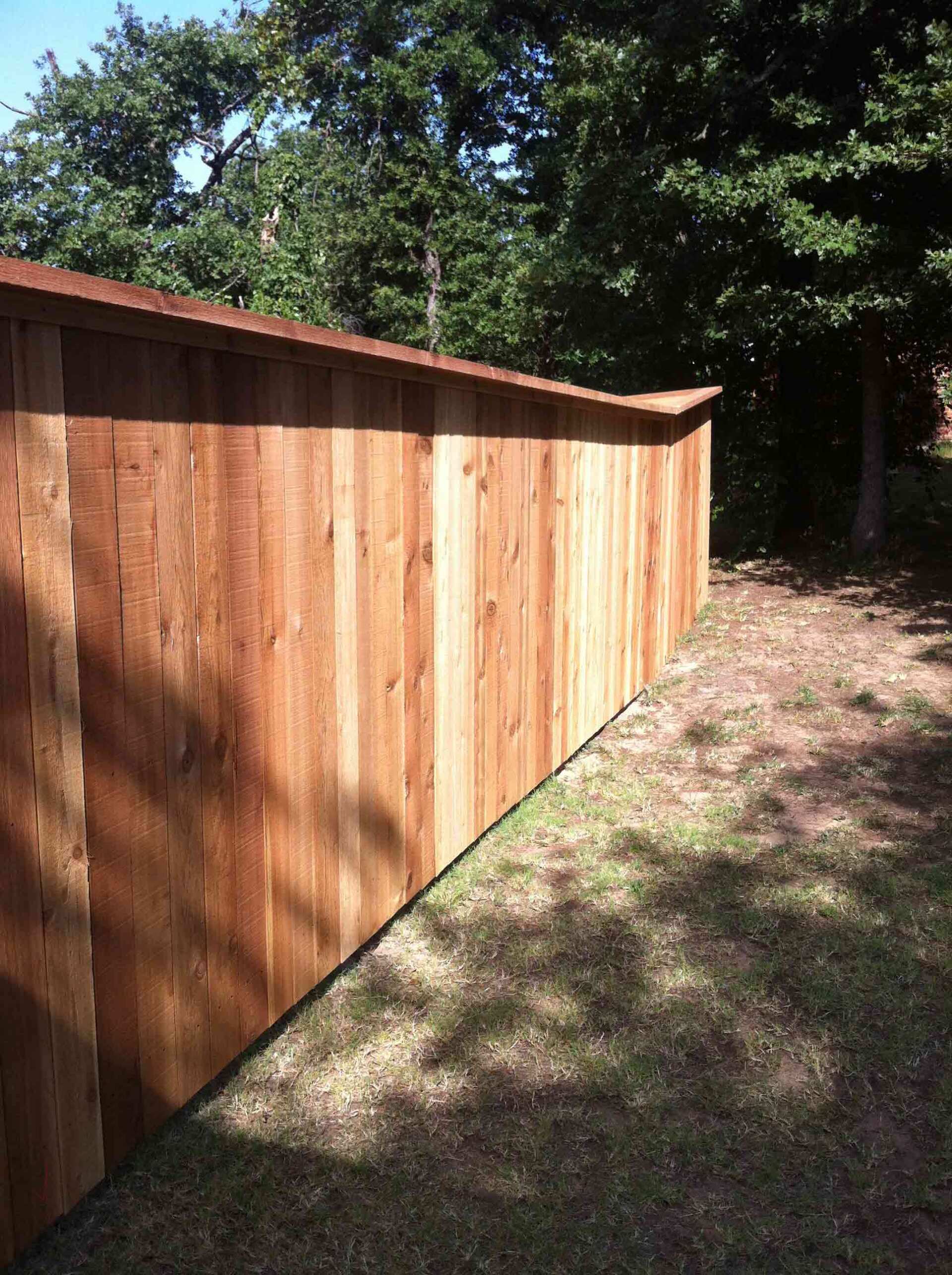 A wooden fence is sitting on top of a lush green field.