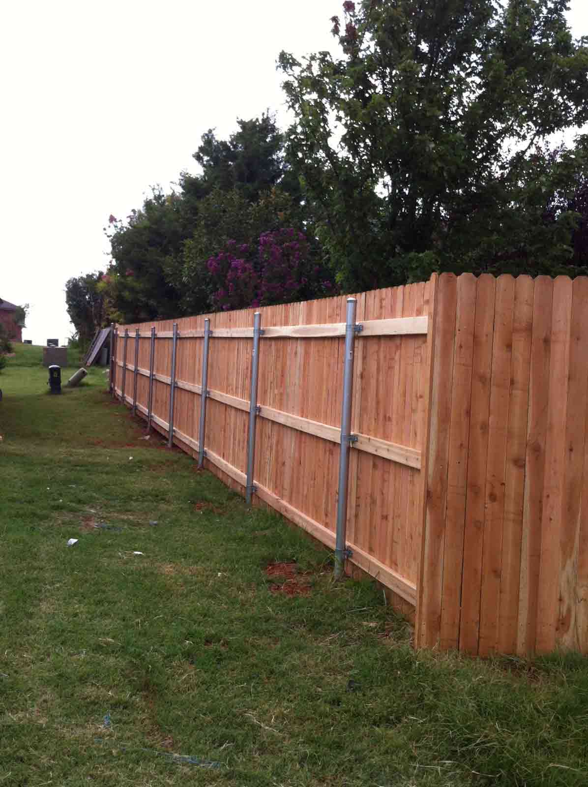 A wooden fence is in the middle of a grassy field
