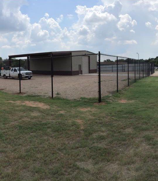 A truck is parked in front of a building behind a chain link fence