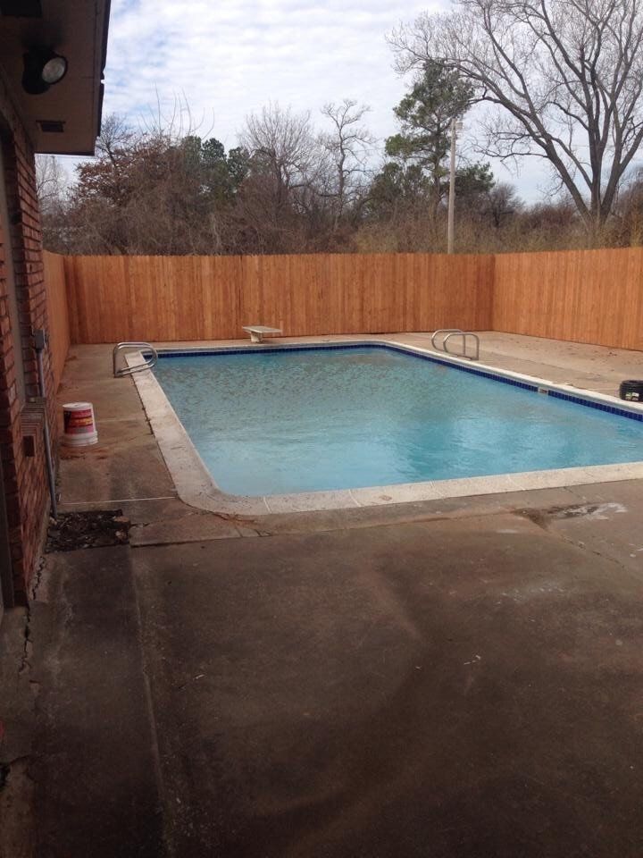 A large swimming pool with a wooden fence around it