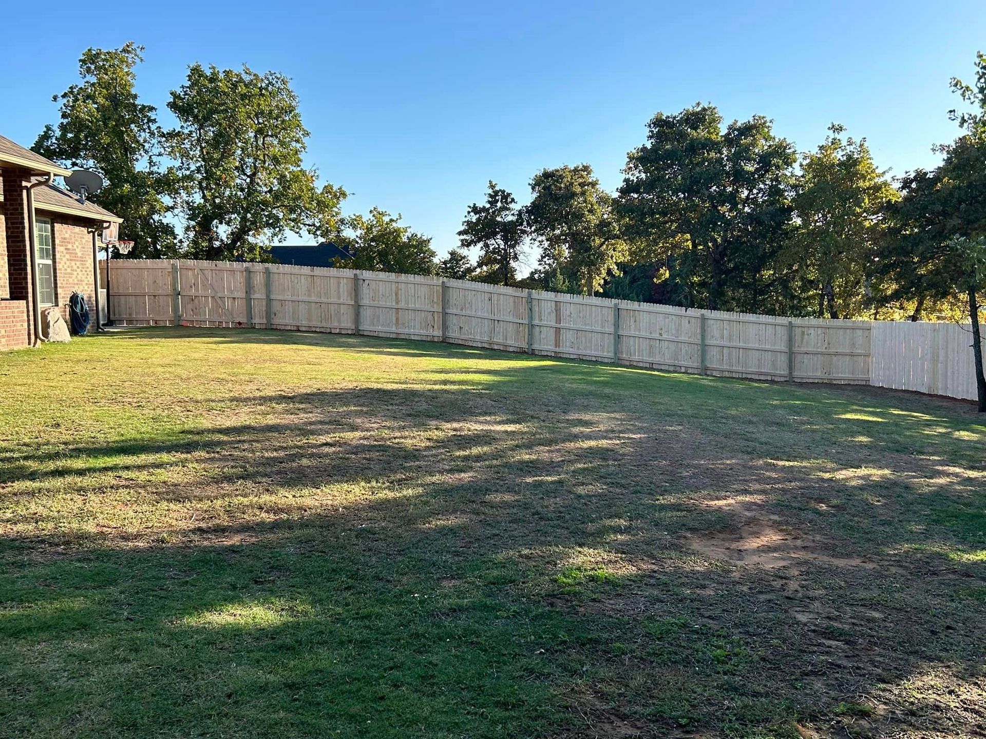 A large yard with a white fence and a house in the background.