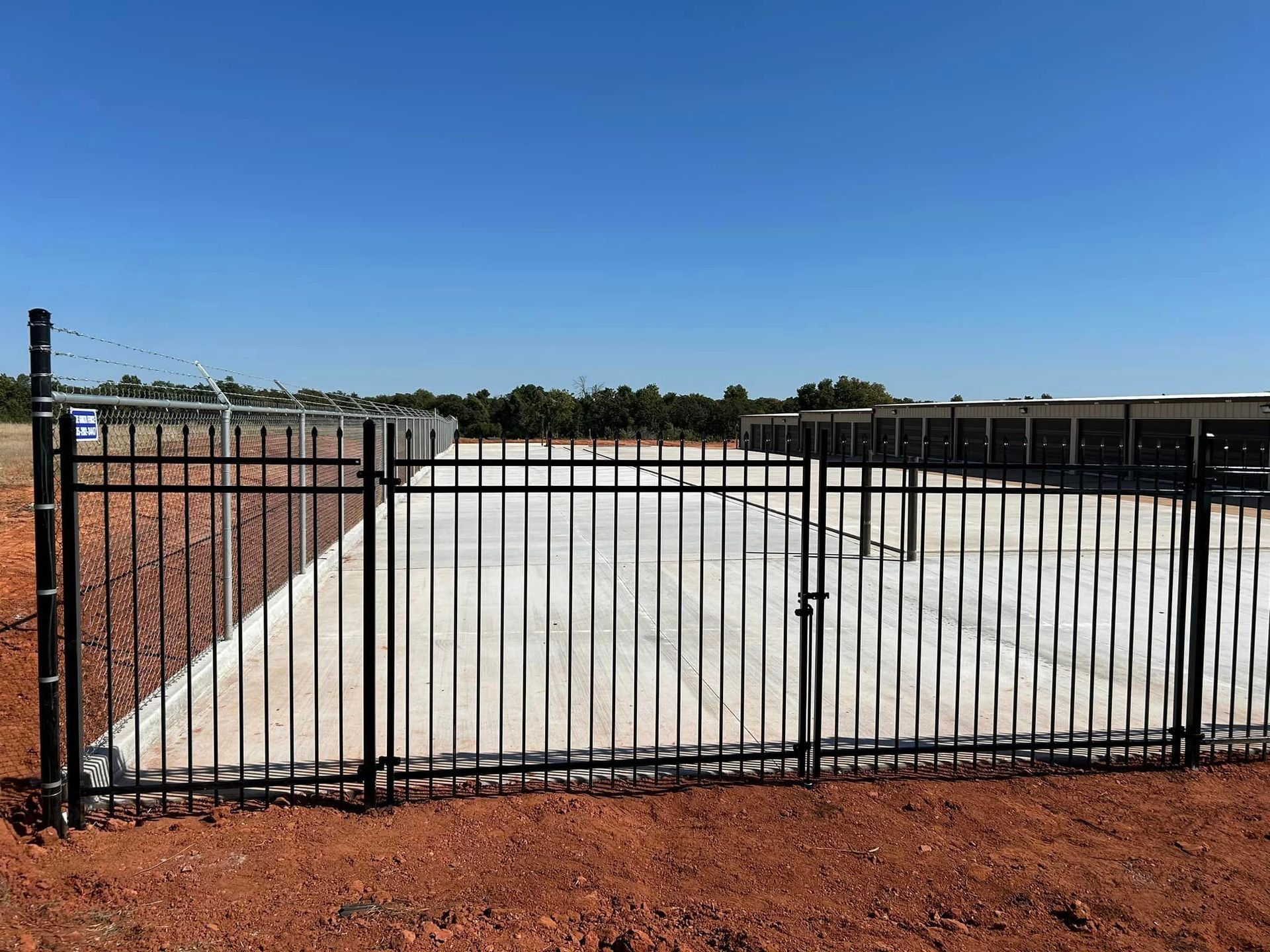 A black metal fence surrounds a concrete driveway.
