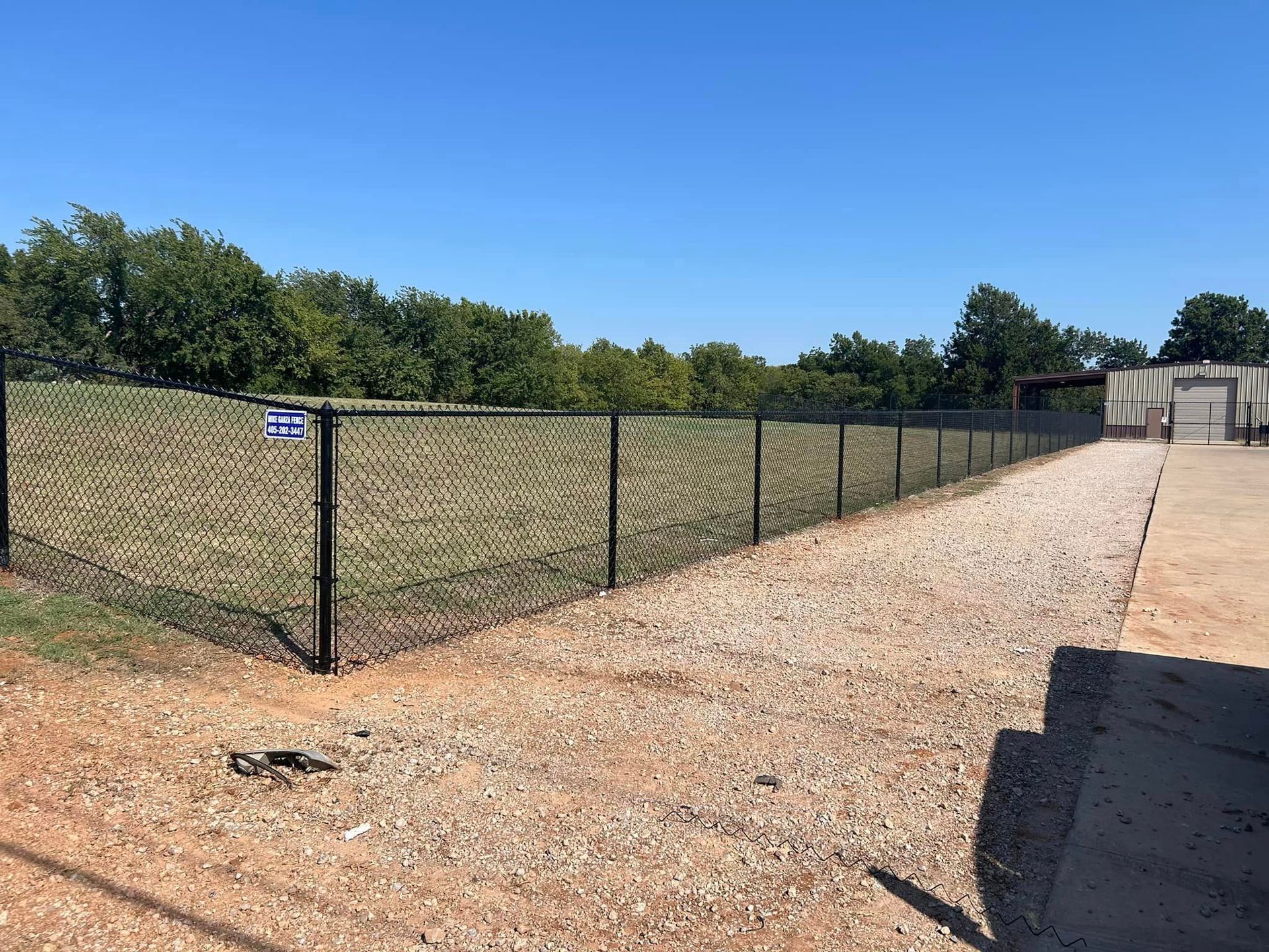 A chain link fence is surrounding a gravel road.