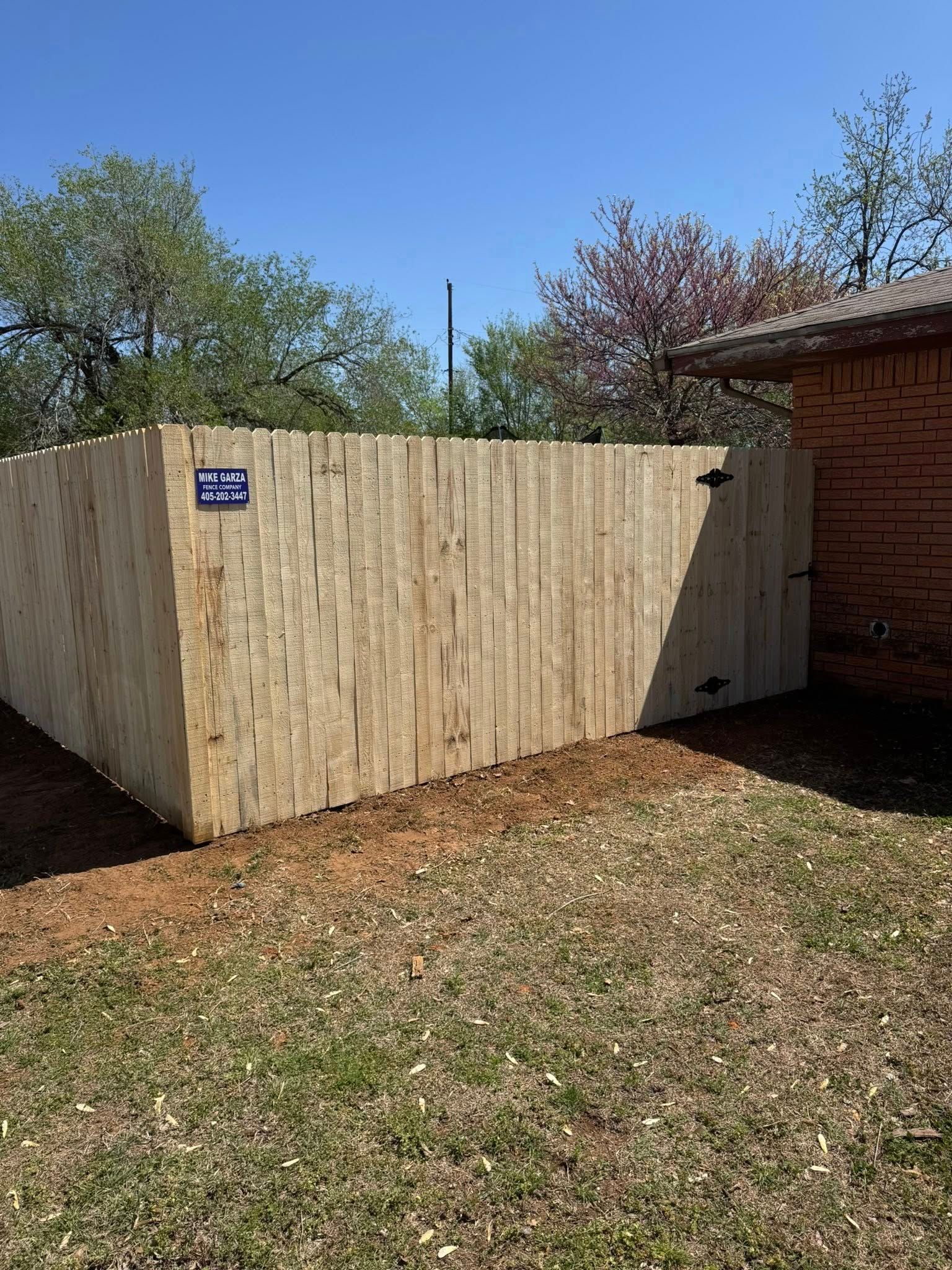 A wooden fence is in the backyard of a house.