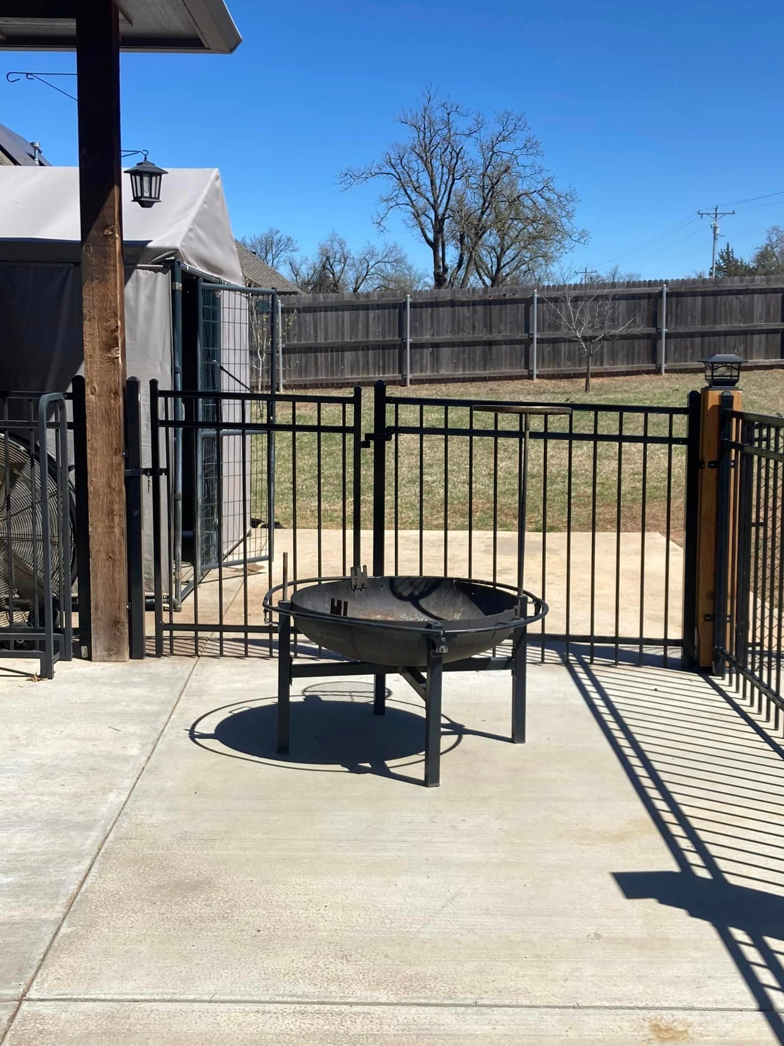 A fire pit sits on a patio next to a fence