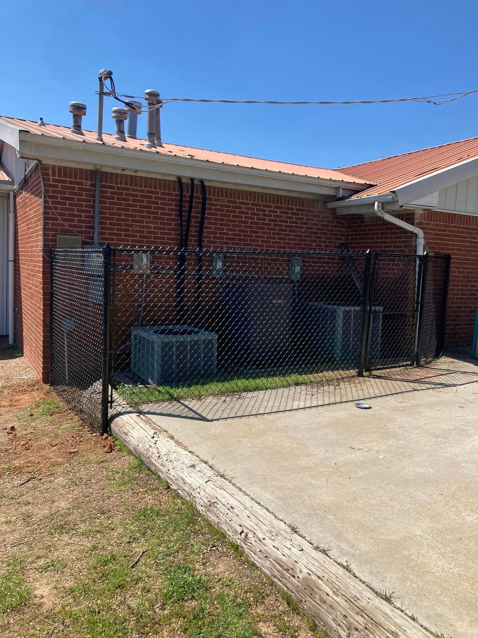 A brick house with a chain link fence in front of it.