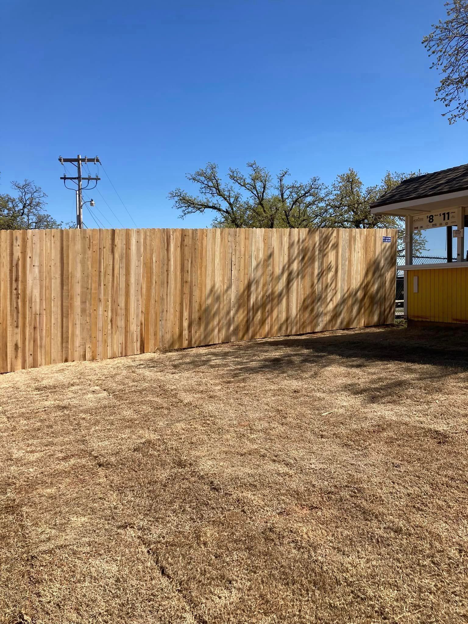 There is a wooden fence in the middle of a yard.