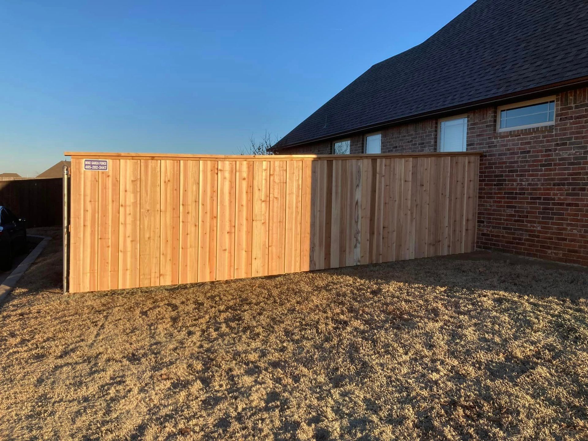 A wooden fence is in front of a brick building.