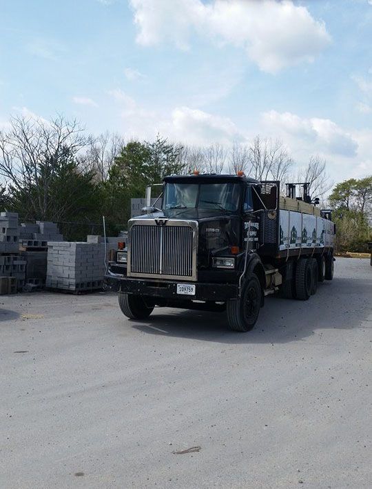 A black semi truck is parked in a parking lot.