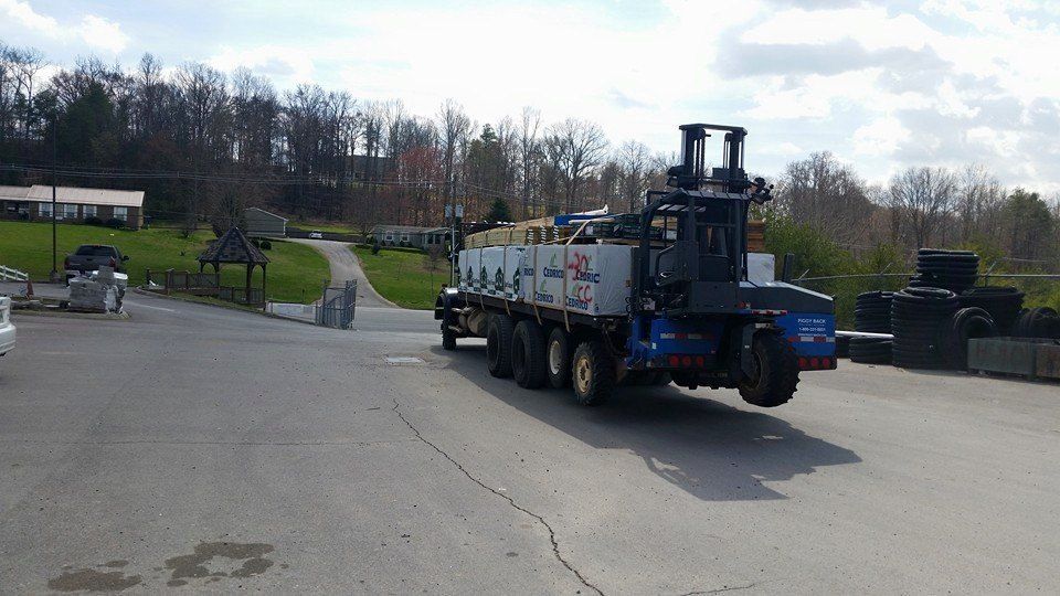 A truck with a forklift on the back is driving down a road.