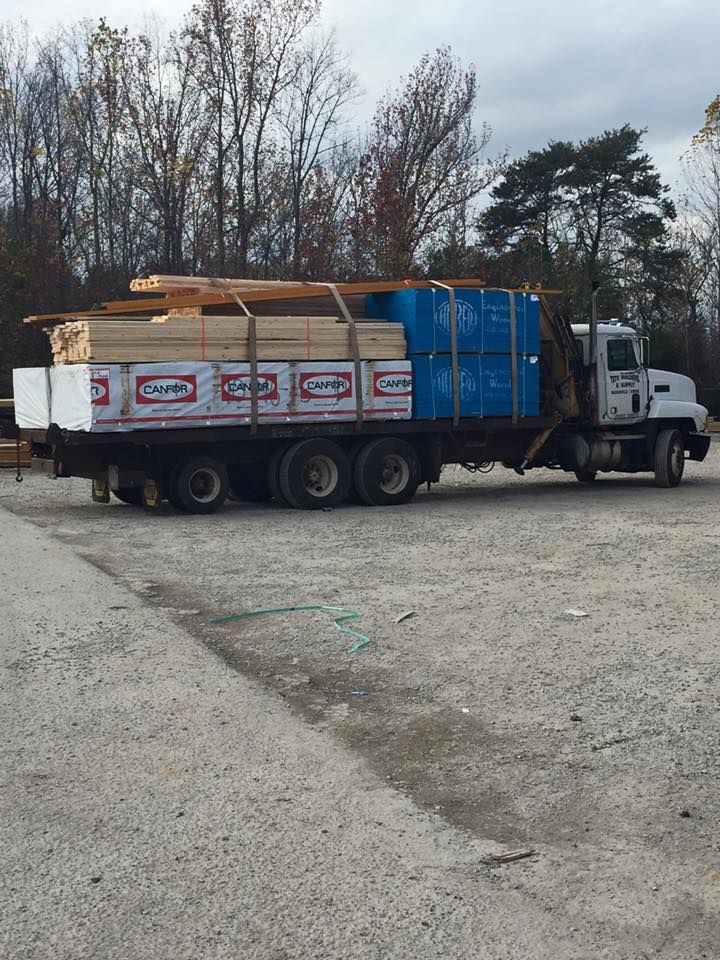 A truck is carrying a load of wood in a parking lot.