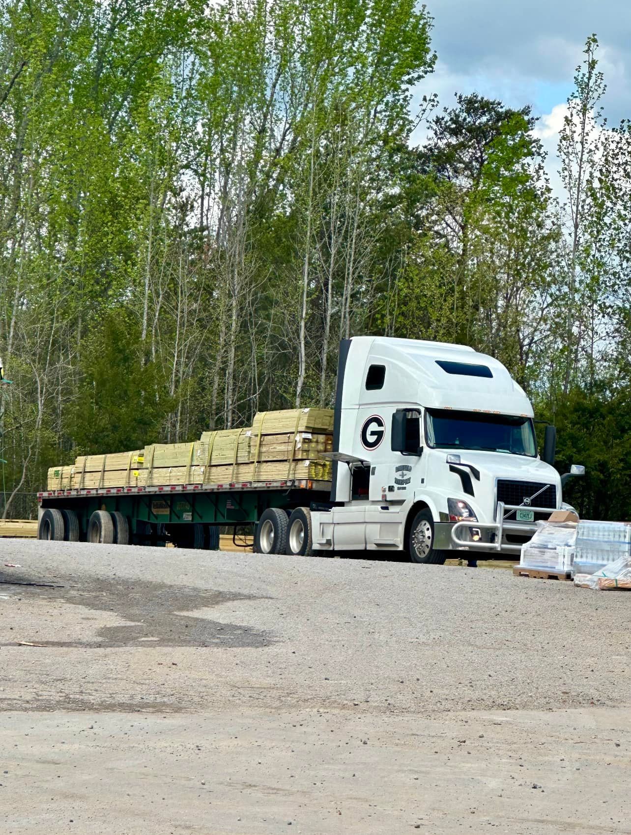 A white semi truck with the letter g on the side