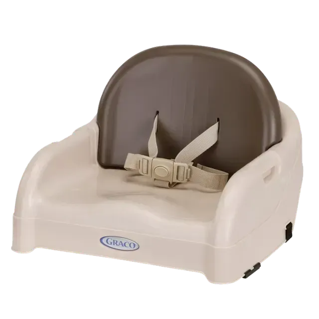 A beige and brown Graco booster seat for a baby with a safety harness.