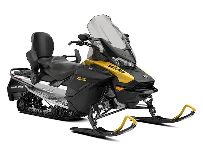 Yellow and black Ski-Doo snowmobile with a passenger seat, windshield, and black saddlebags on snow.