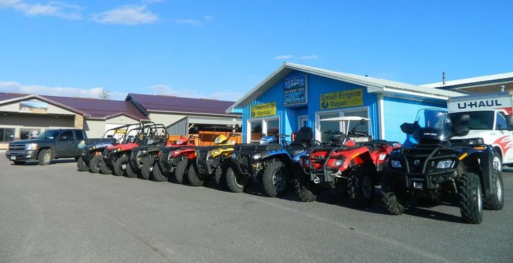 ATVs parked in front of a blue building with business signage, sunny day.